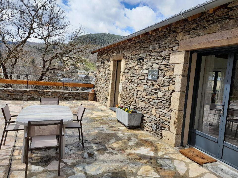 a patio with a table and chairs in front of a stone building at Maison de l'aire in Fraissinet-de-Fourques