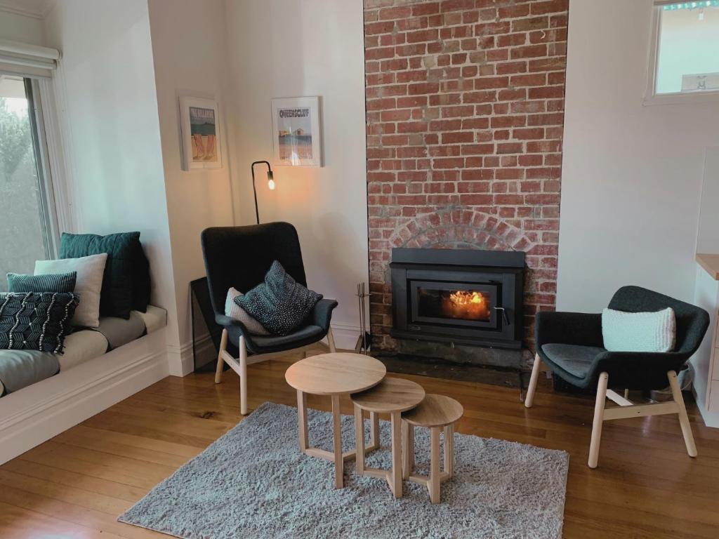 a living room with a fireplace and chairs and a table at Galway Cottage in Queenscliff