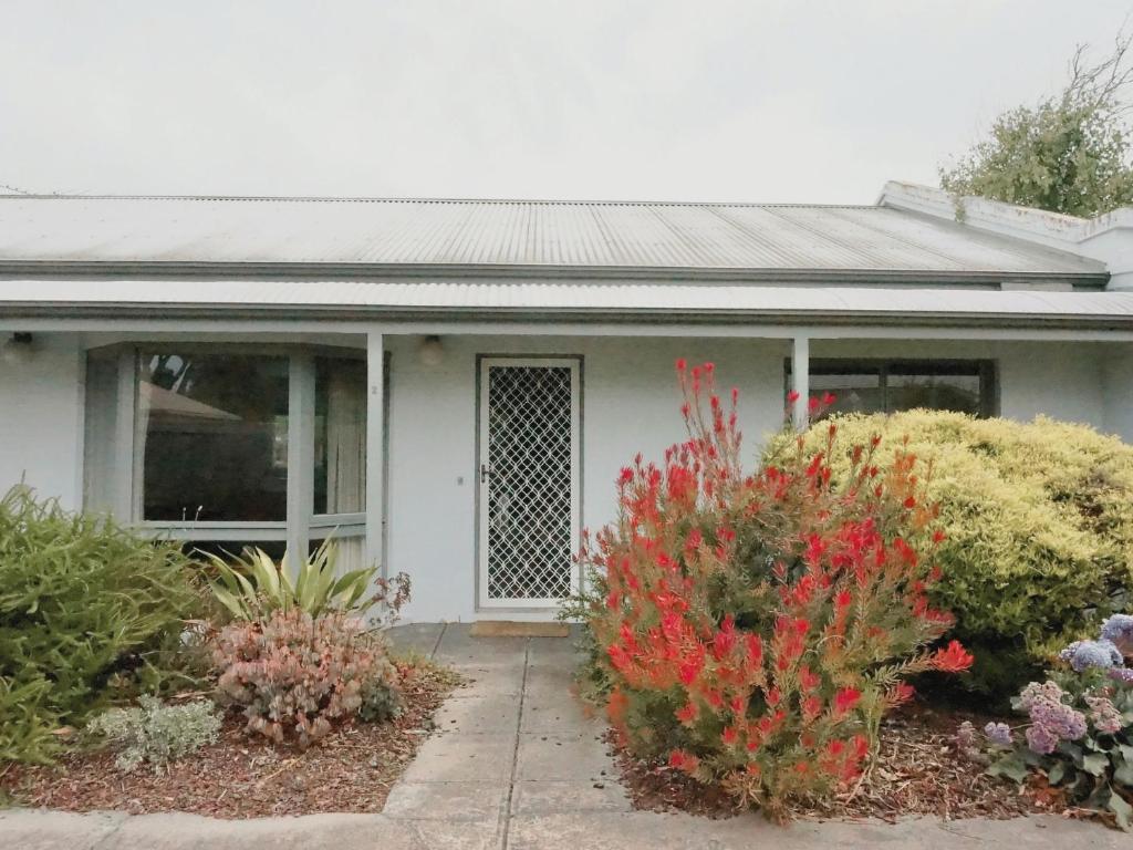 a white house with flowering plants in front of it at Glan Mor in Queenscliff