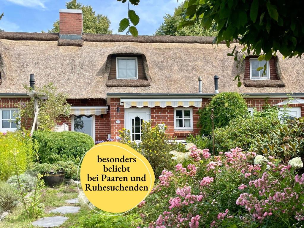 an old house with a sign in the garden at Reetdachhaus in Seenähe, Ruhige Lage, Kamin & Terrasse in Seedorf