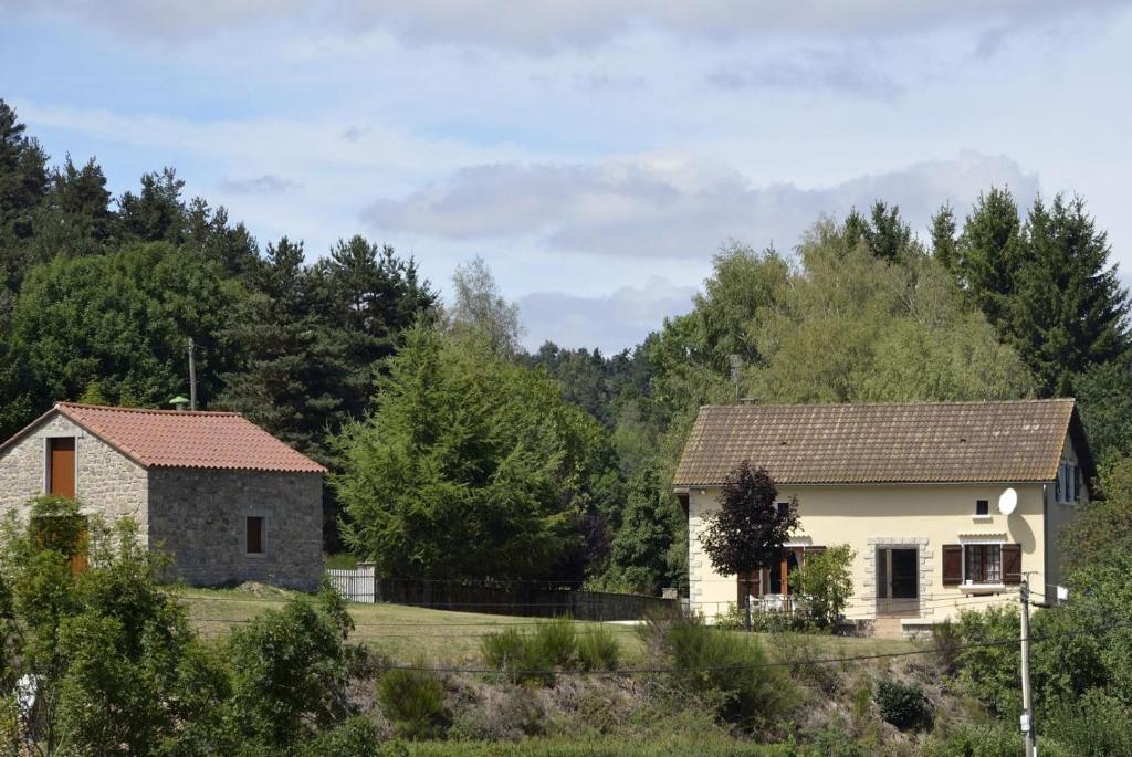 two houses in a field with trees in the background at La parrot en margeride in Pierrefiche
