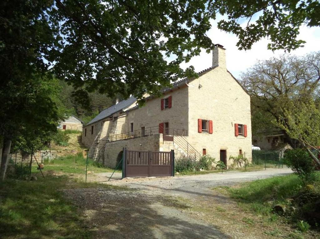 a large white building with red windows and a gate at Le gite de granade in Barjac
