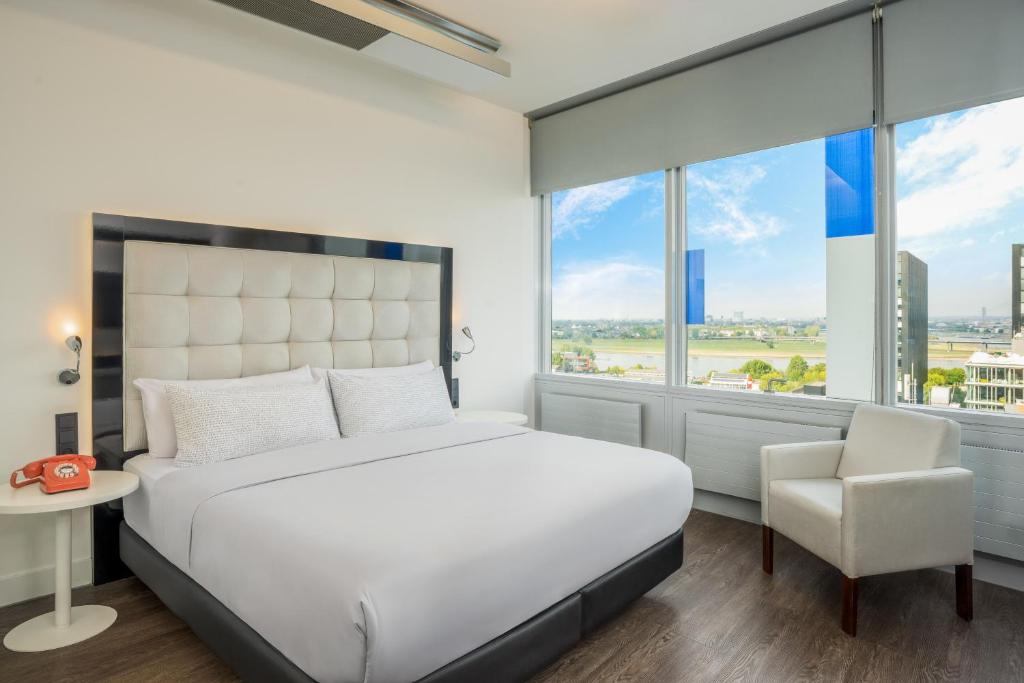 a bedroom with a white bed and a chair at INNSiDE by Meliá Düsseldorf Hafen in Düsseldorf