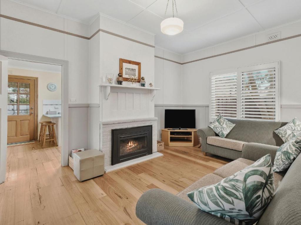 a living room with a couch and a fireplace at Maison Cottage in Queenscliff