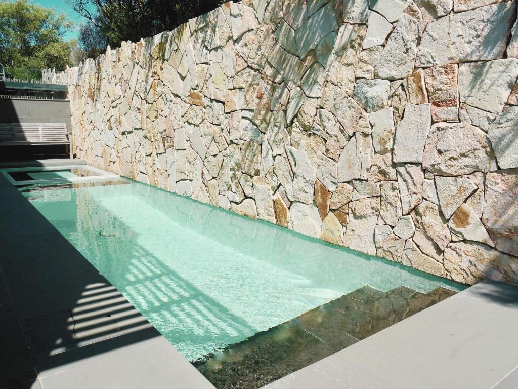 a swimming pool next to a stone wall at Sand Dunes in Point Lonsdale