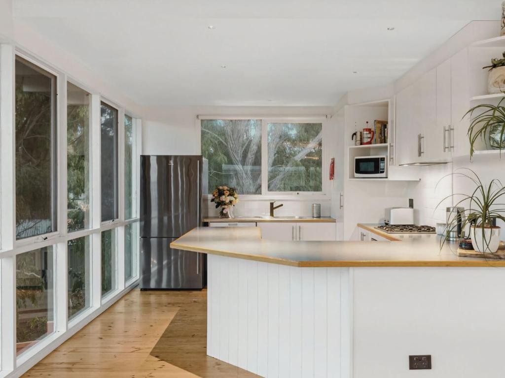 a kitchen with white cabinets and a large window at The Springs in Point Lonsdale