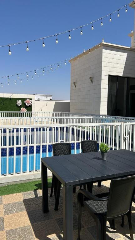 a black table and chairs in front of a pool at هلا شاليه اتين in Salalah