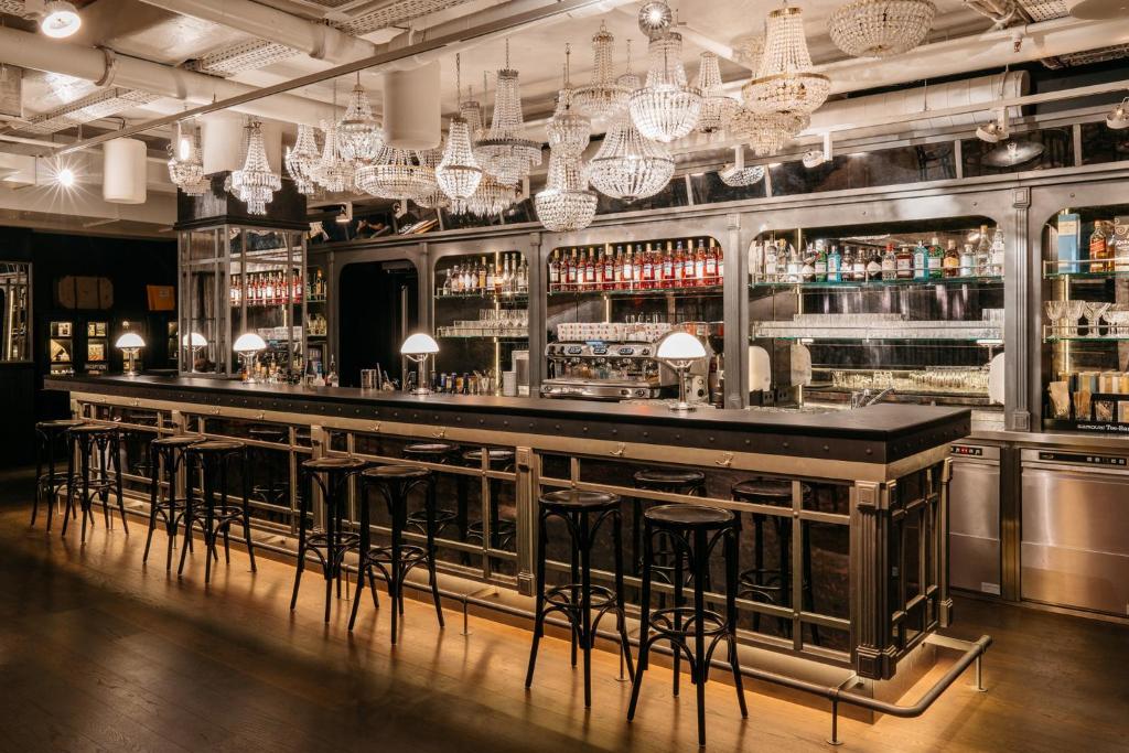 a bar with stools in a room with chandeliers at Ruby Lissi Hotel Vienna by IHG in Vienna