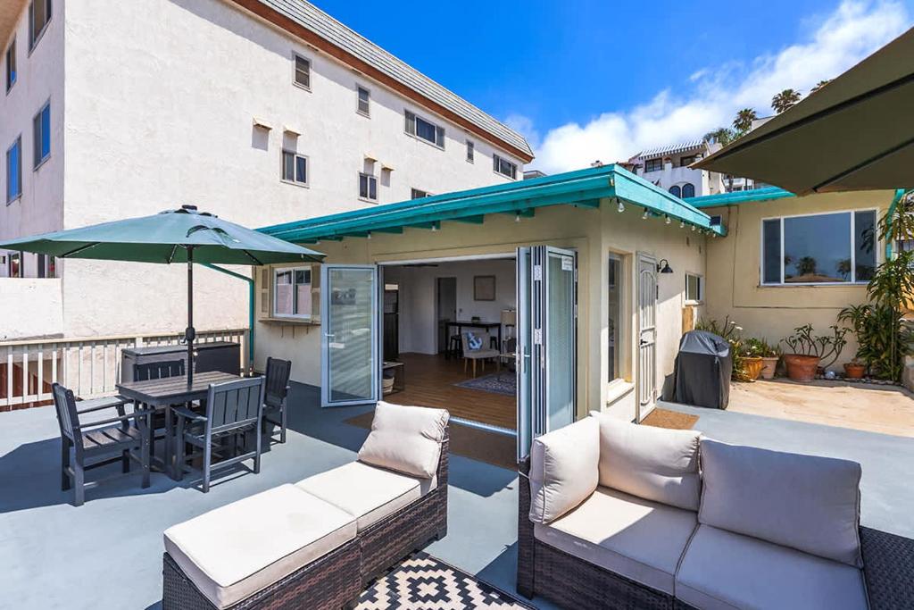 a patio with a couch and a table with an umbrella at Steps to the pier! in San Clemente