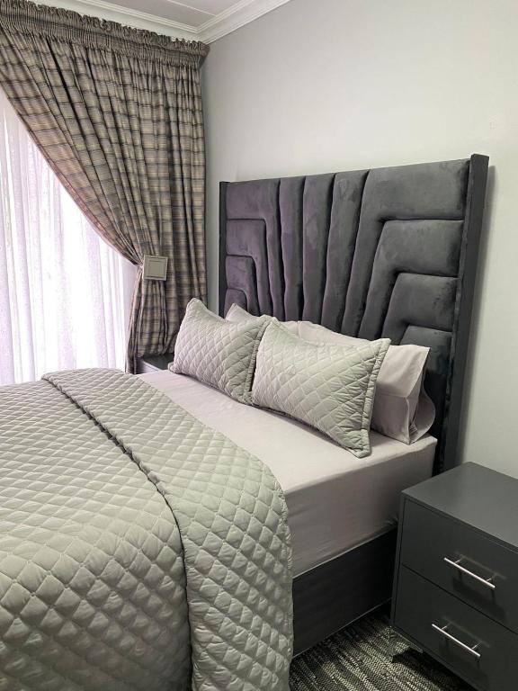 a bedroom with a large bed with a large headboard at Smileys accomodation in Standerton