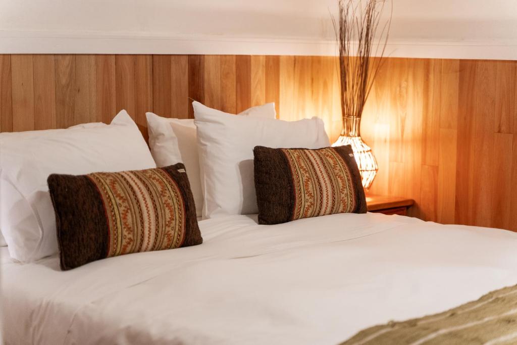 a large white bed with two pillows on it at Hotel Aquaterra in Puerto Natales