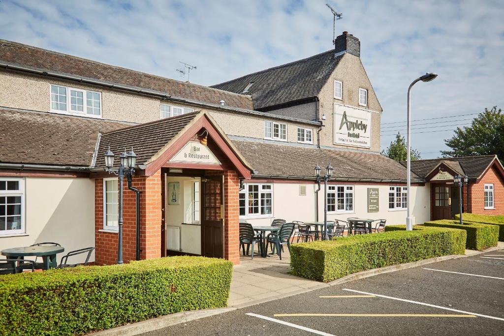 a building with tables and chairs in a parking lot at The Appleby Inn Hotel in Appleby Magna