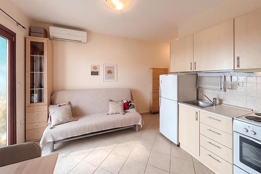 a small kitchen with a couch and a refrigerator at Petra Afytos holiday in Afitos