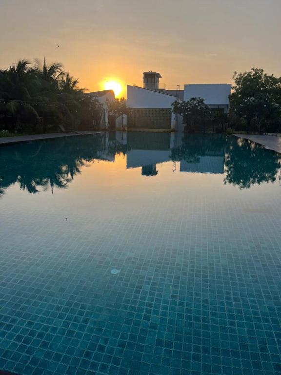 a large swimming pool with a sunset in the background at Perolas Homestay in Xóm Chum Găng