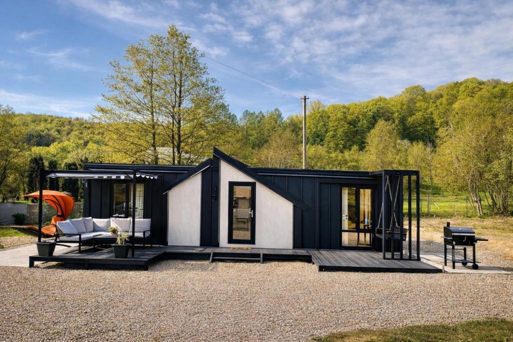 a black and white tiny house with a porch at The Forest Retreat in Mihăeşti