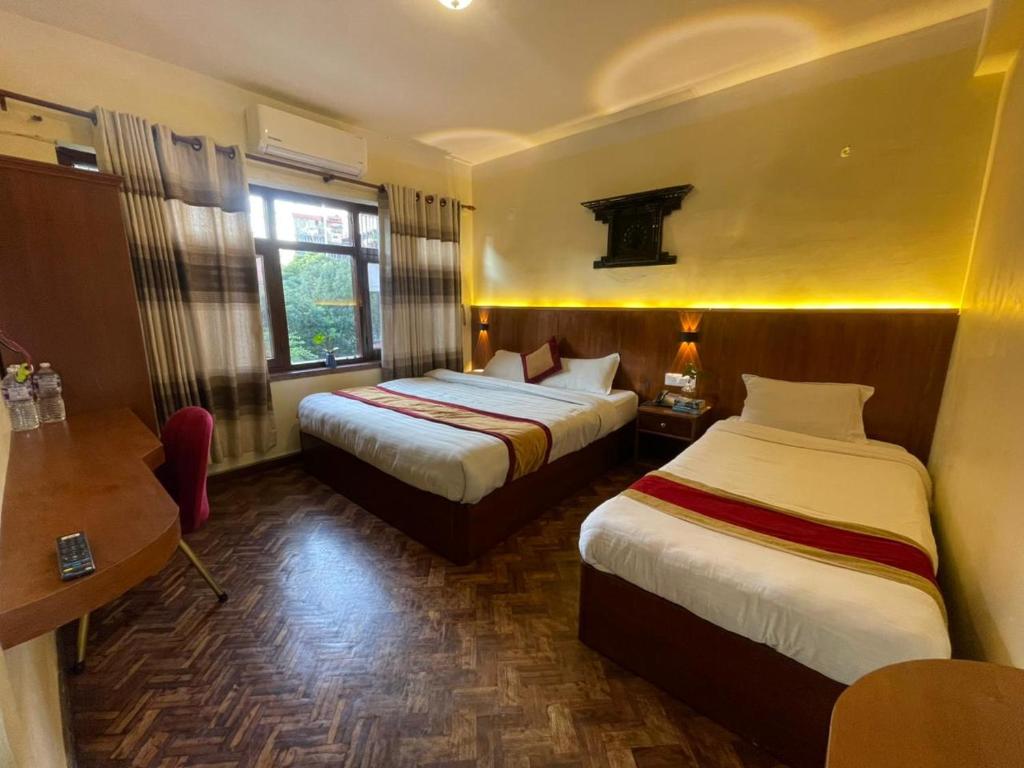 a hotel room with two beds and a desk at Hotel Atlantic in Kathmandu