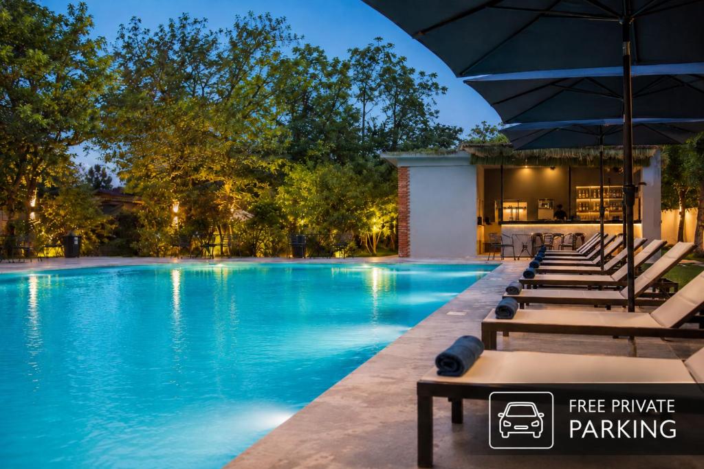 a pool at night with lounge chairs and an umbrella at Kobuleti Garden Inn in Kobuleti