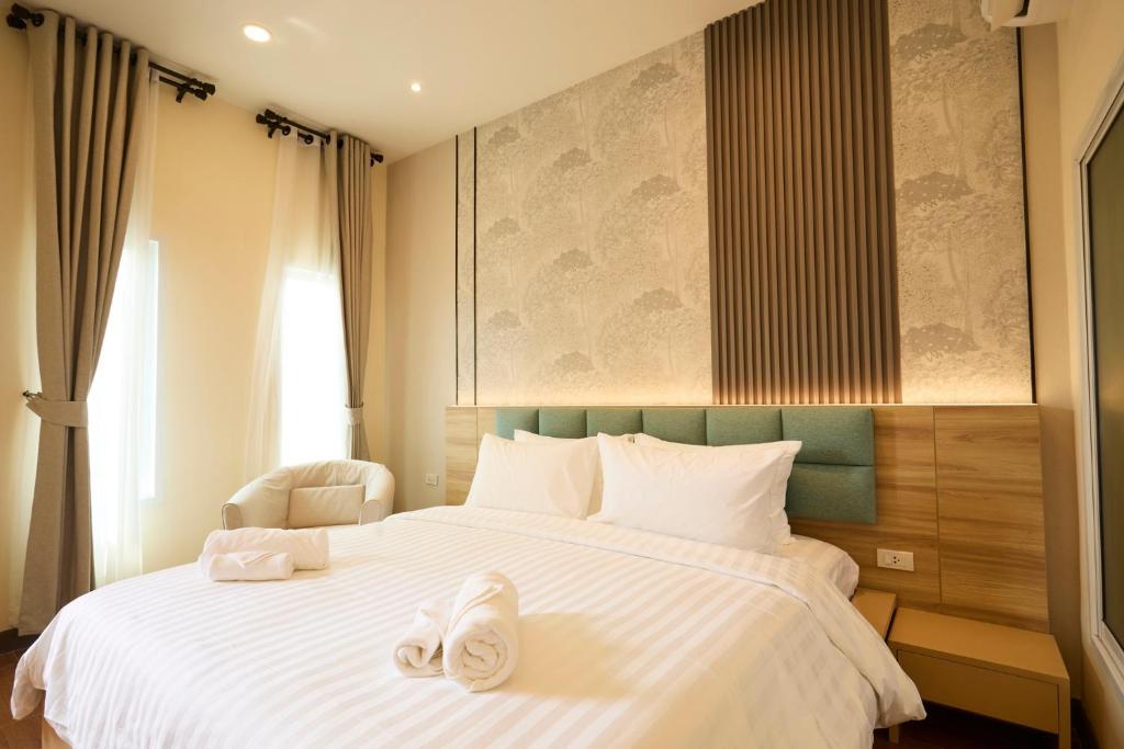 a bedroom with a large white bed with white shoes on it at Rocco Hotel Bangsaen in Ban Laem Thaen