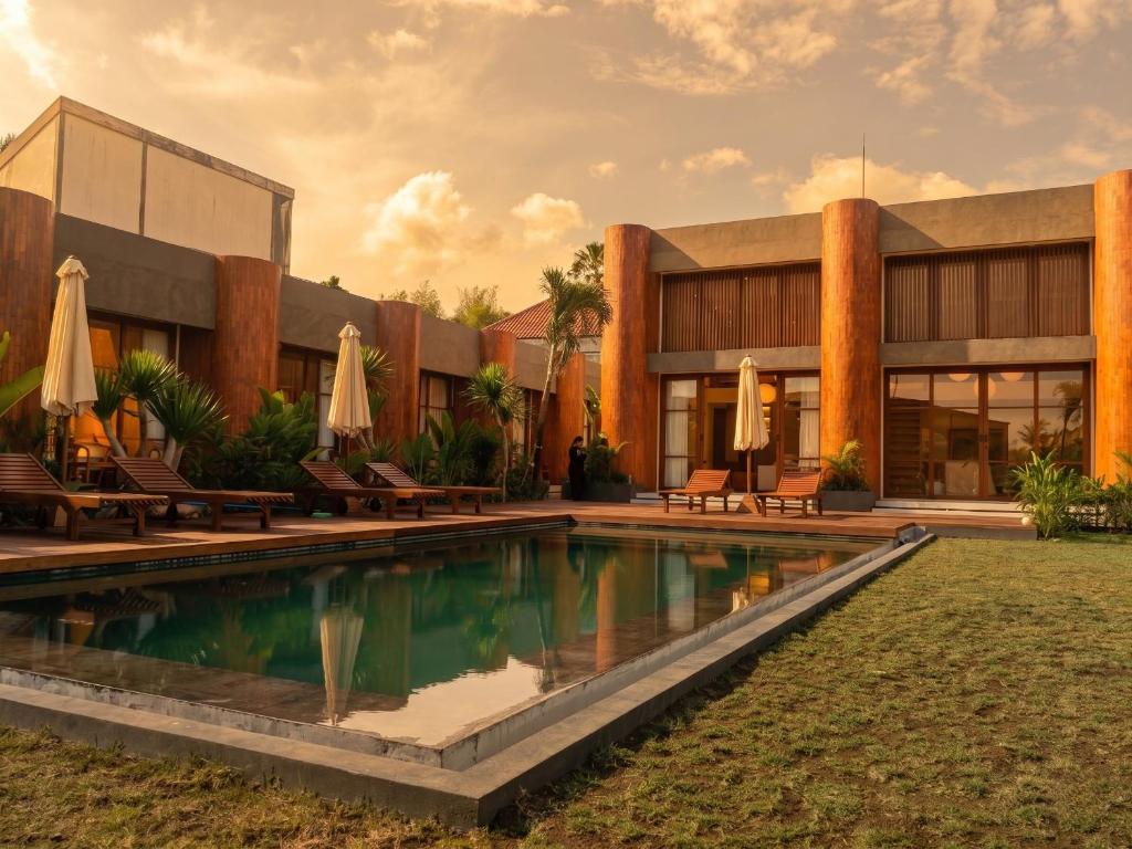 a resort with a swimming pool in front of a building at Frontera Nyanyi in Tabanan