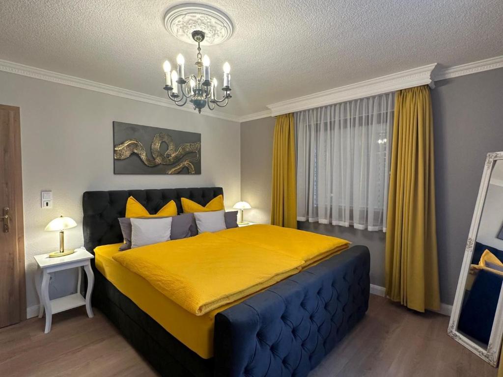 a bedroom with a yellow bed with a chandelier at Ferienwohnung Zum Gartenparadies in Oppach