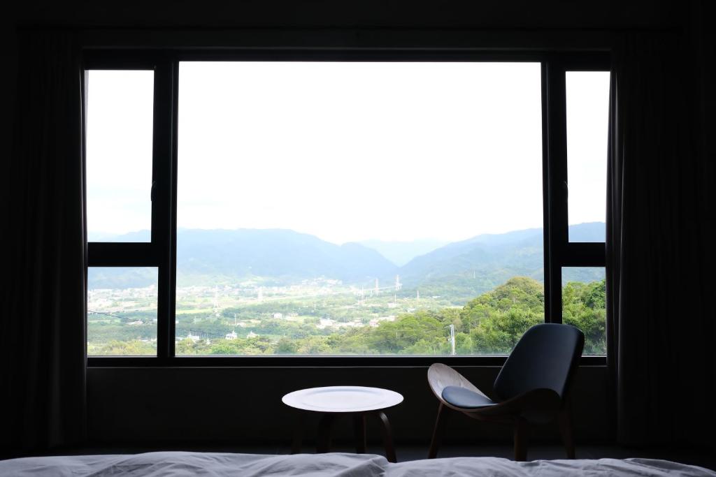 a bedroom with a bed and a table and a window at Tao Ye BnB in Miaoli