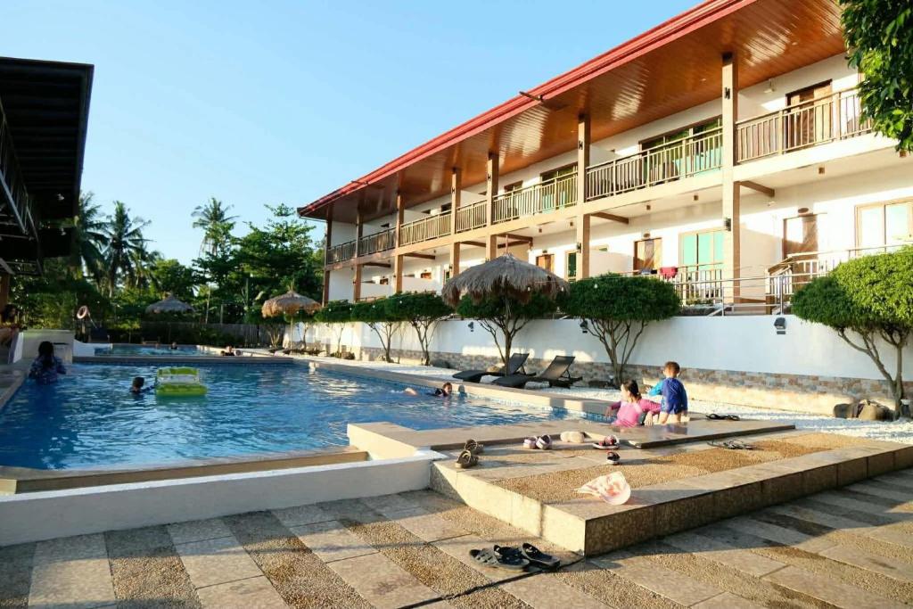 a hotel swimming pool with people sitting in it at Terra Verde Resort Guindulman Bohol in Guindulman