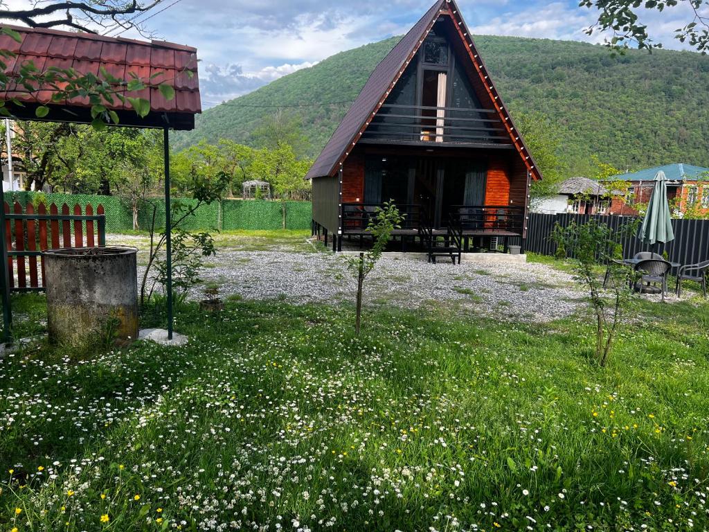 a small house with a red roof in a field of flowers at Tuta Cottage near Martvili Canyon in Martvili
