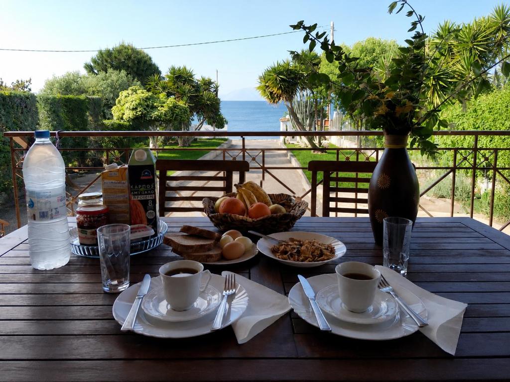 a wooden table with breakfast food and a bottle of water at Villa Bella Loukisia Seafront 5BR Villa for 10 Near Athens in Loukísia