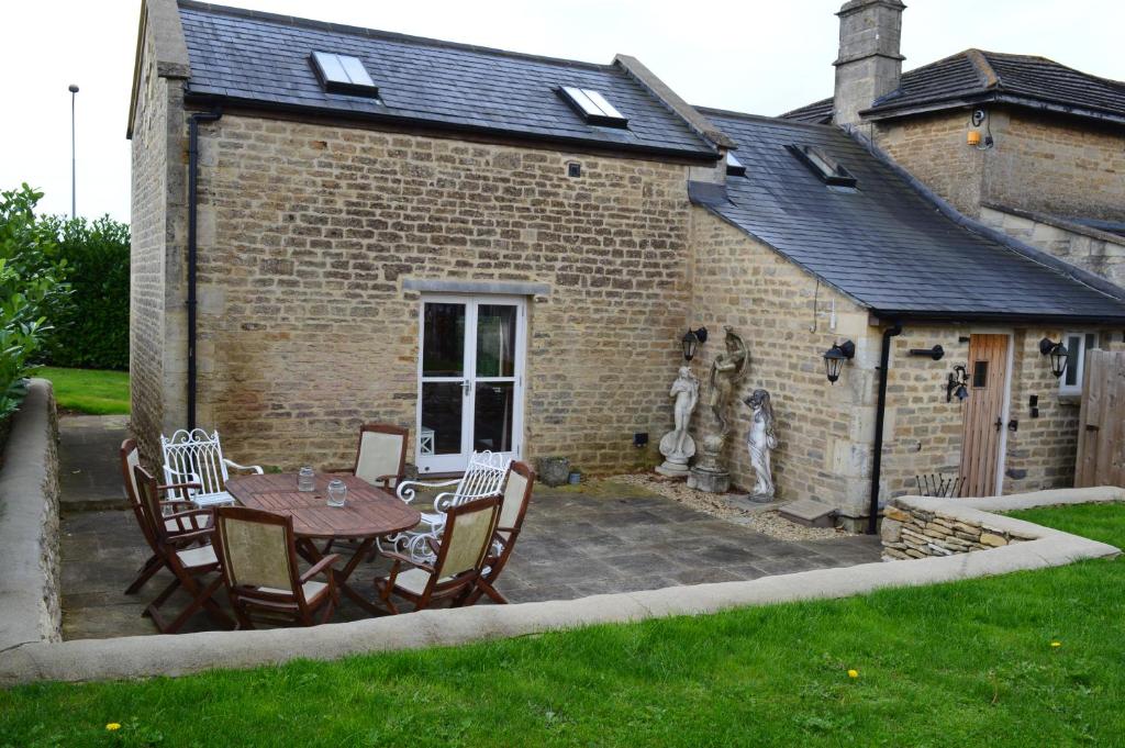 a patio with a table and chairs in front of a building at Crossroads Farm - Queen Anne's Stable in Box