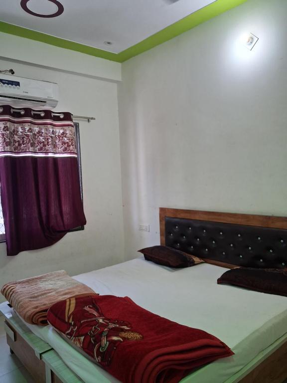 a bedroom with a bed and a curtain on a window at Khaatuwaale Guest House in Khātu