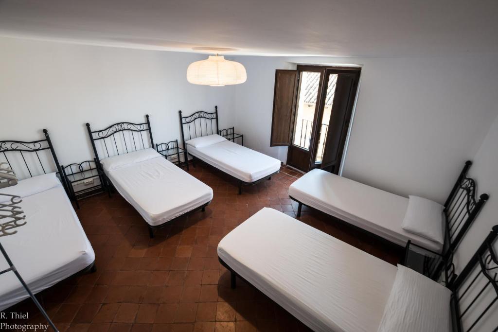 a room with three white beds and a chandelier at Albergue Rosalia / Pilgrim Hostel in Castrojeriz