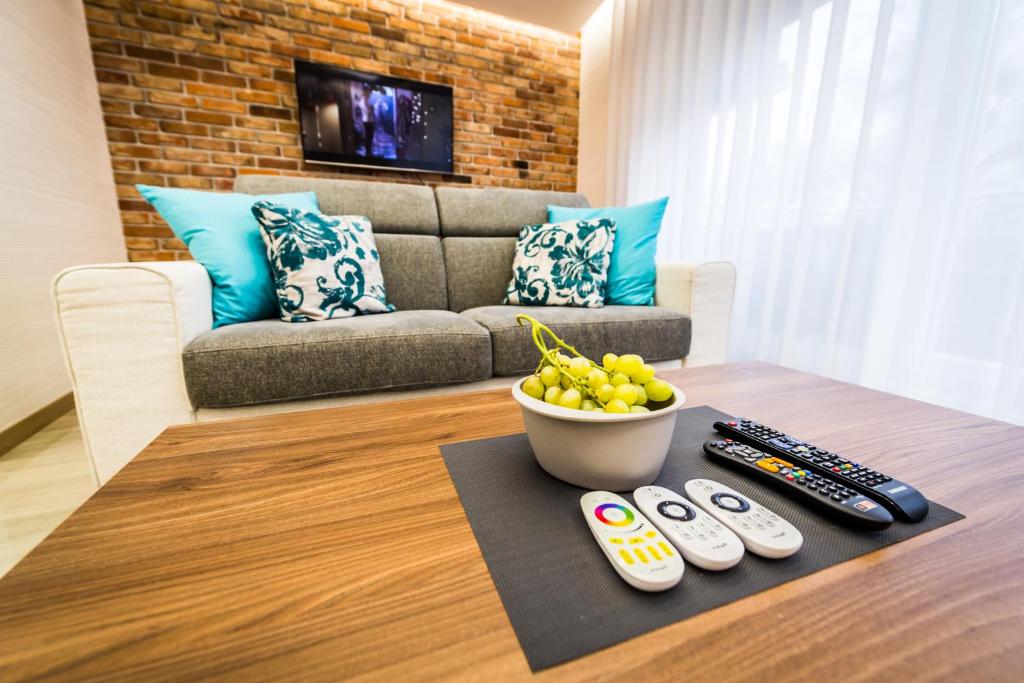 a living room with a couch and a table with remote controls at Komfortowy Apartament nad Niegocinem in Giżycko
