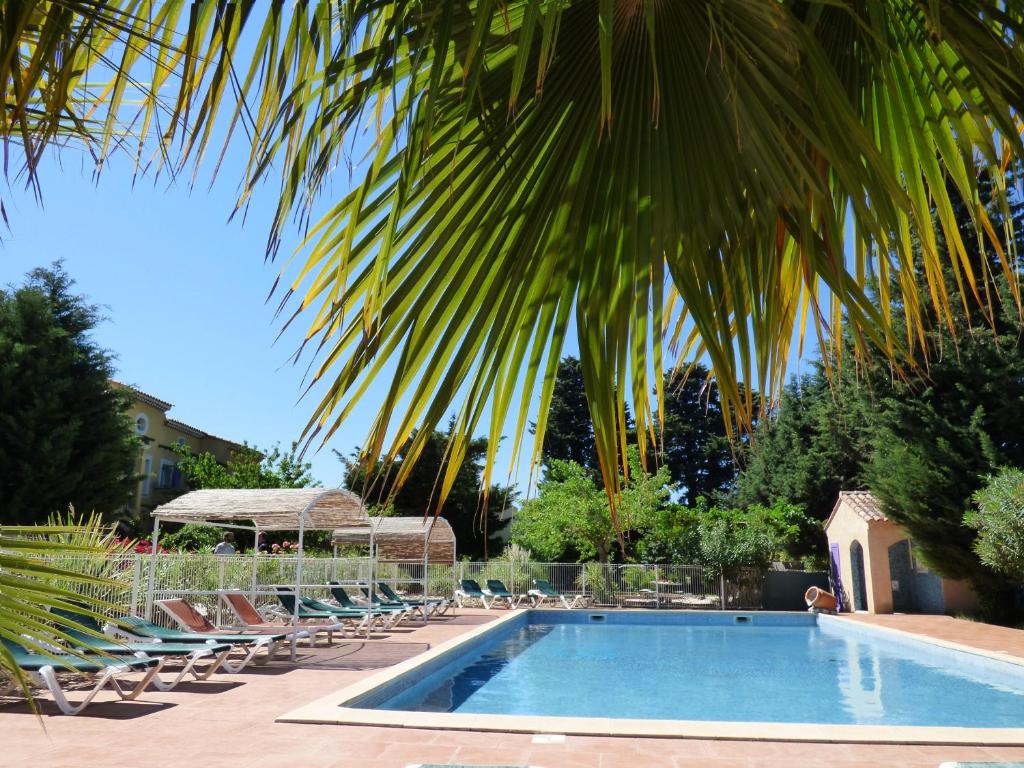 - une piscine avec des chaises longues et un palmier dans l'établissement Appart'Hotel Festival Sud Aqua - Avignon TGV, à Avignon