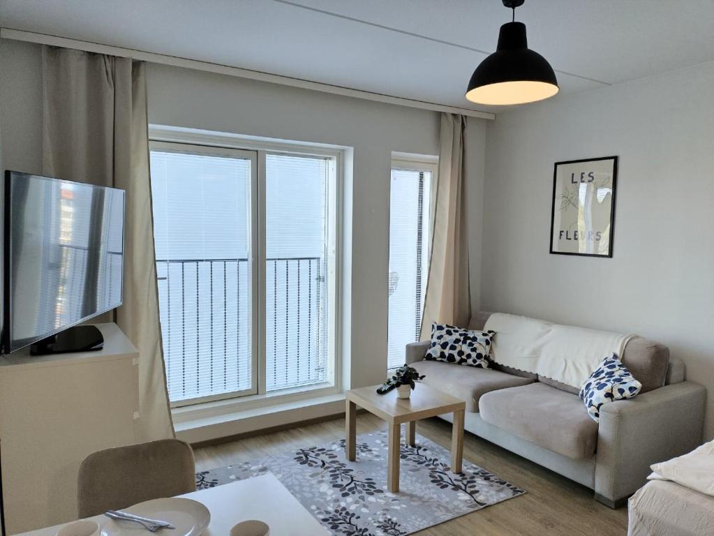 a living room with a couch and a large window at Foliate Living Varpu in Jyväskylä