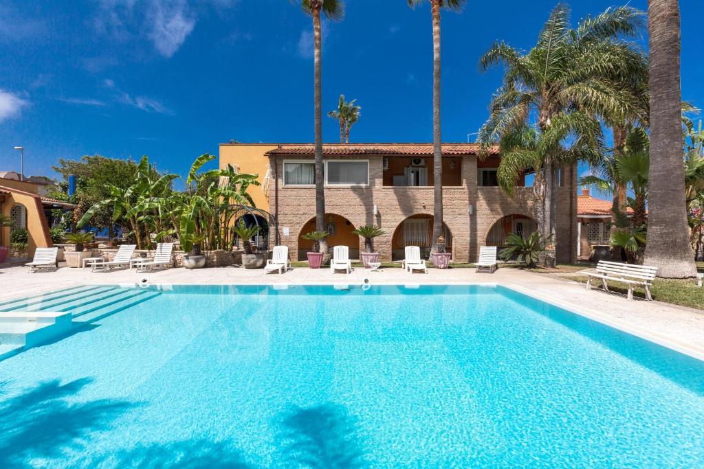 a swimming pool in front of a house with palm trees at Villa Thalissa by Perle di Puglia in Taranto