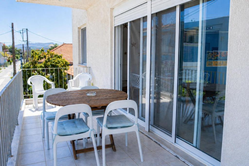 a balcony with a wooden table and white chairs at Marilia GuestHouse - Seaside Retreat in Evia in Agia Anna