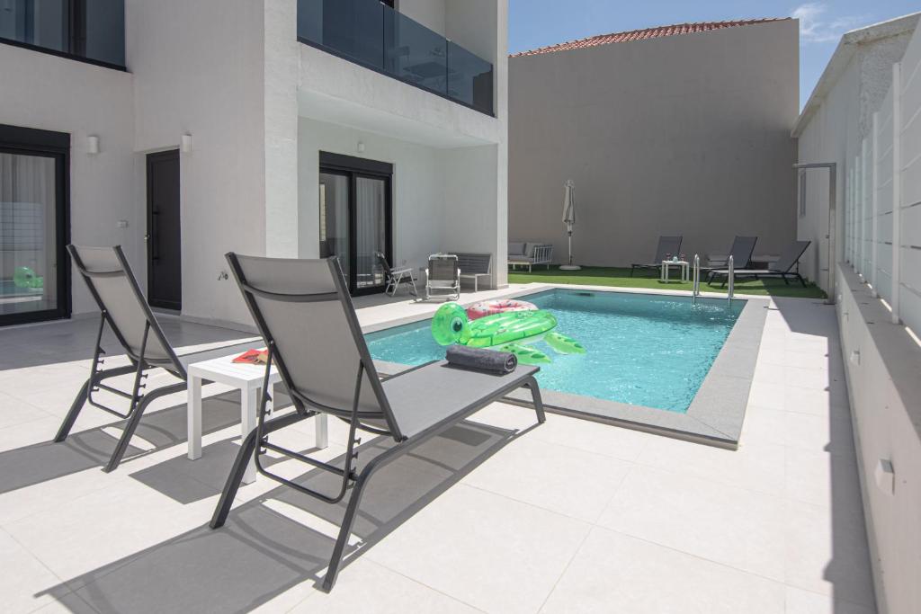 a swimming pool with two chairs and a pool toy at Tolis Exclusive Villa in Kissamos