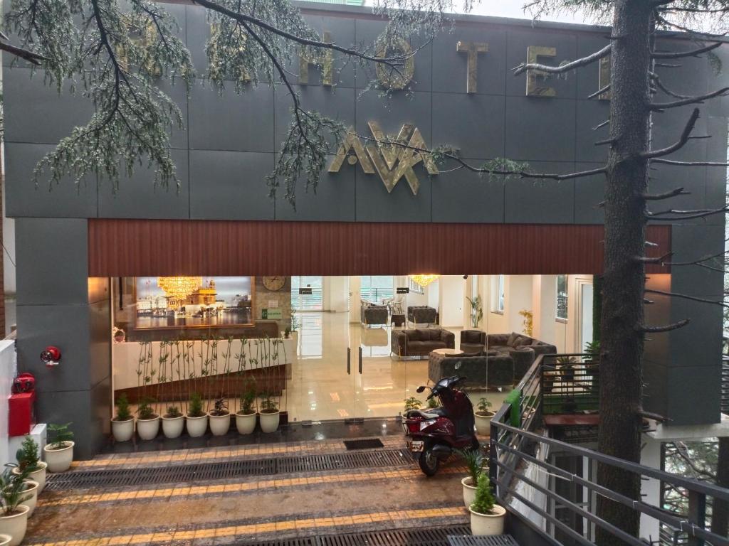 a man on a motorcycle parked in front of a building at RR Hotel & Resort by Sonachi in Dharamshala