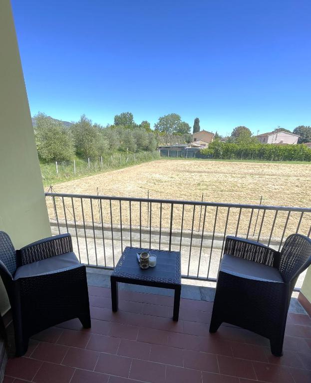 a balcony with two chairs and a table and a field at A casa di Any in Cascina
