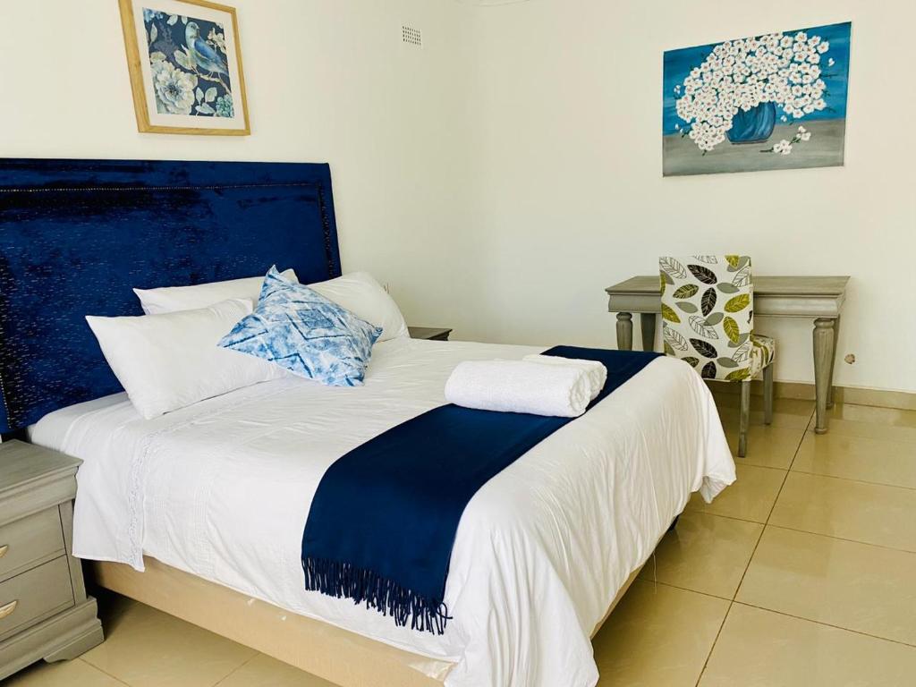 a bedroom with a large bed with blue and white sheets at Meyrick Bed and Breakfast in Harare