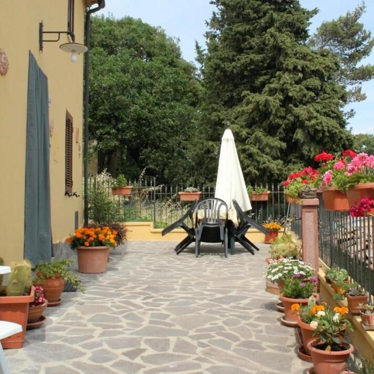 a patio with a table and a umbrella and flowers at Casa Vacanze in Borgo in Monteverdi Marittimo