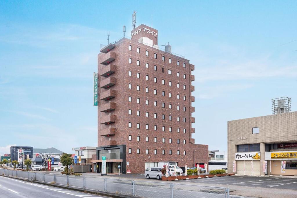 a tall brick building with a clock tower on a street at AZ Inn Handa Inter in Handa