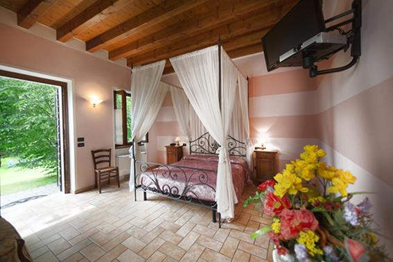 a bedroom with a canopy bed and flowers in a room at Corte Fattori in Monzambano