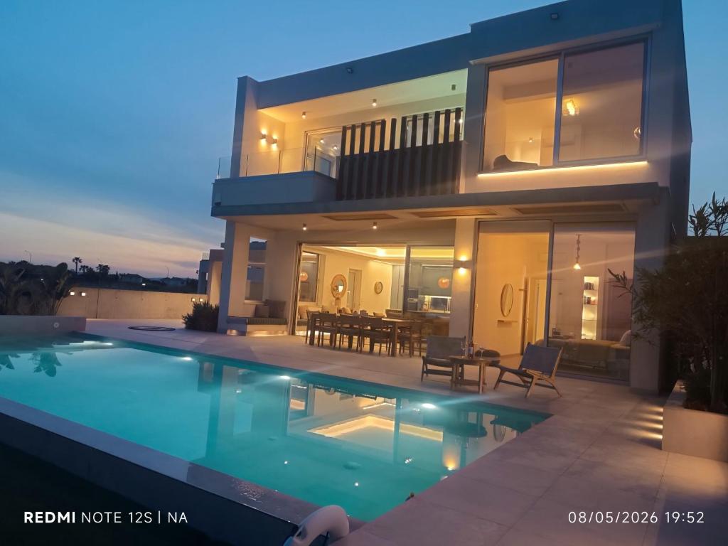 a large house with a swimming pool in front of it at Blue Aura Beach villa Larnaca in Perivolia