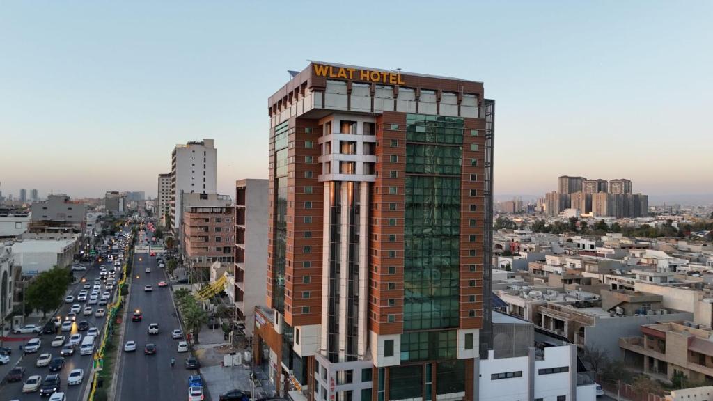 a tall building with a hotel sign on top of it at Wlat Hotel in Erbil