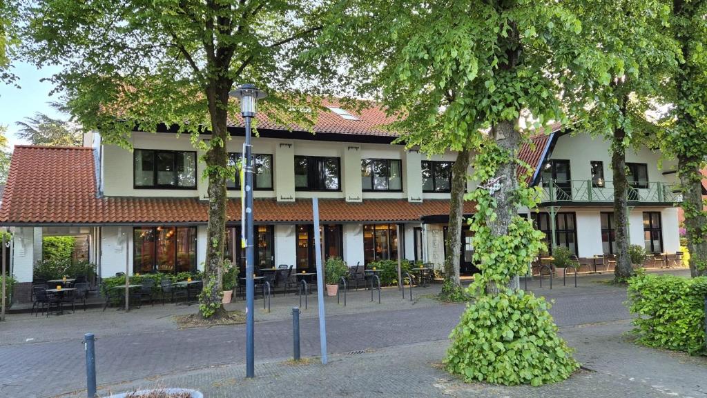 a building with tables and chairs in front of it at Kruller - Hotel B&B in Otterlo
