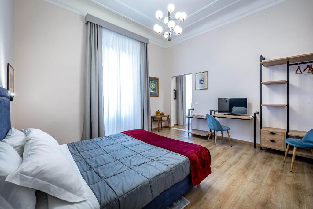 a bedroom with a bed and a desk and a television at Five Suites Mantellate 9 in Florence