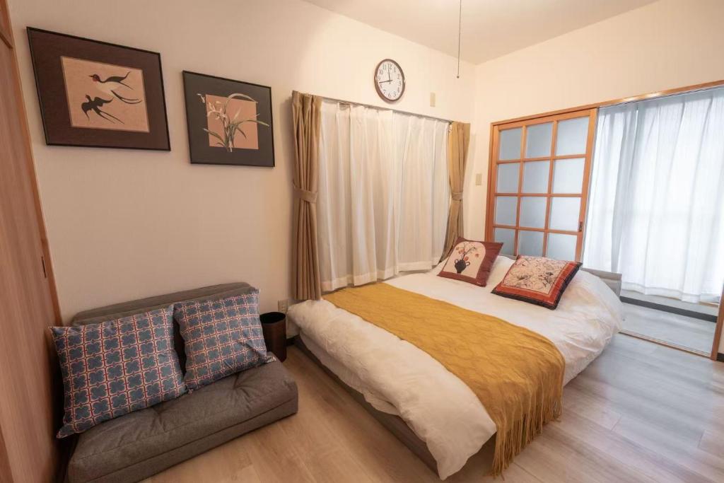 a bedroom with a bed and a chair and a clock at 暖迎の宿 in Tokyo