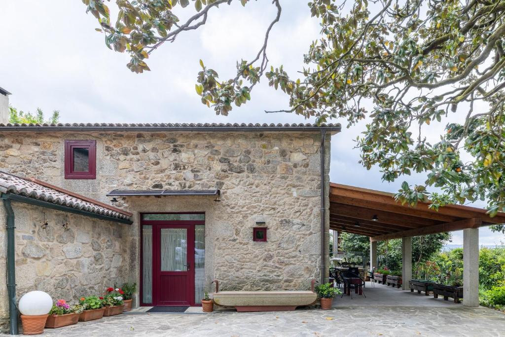 a stone house with a red door and a patio at Vagalume in Vedra