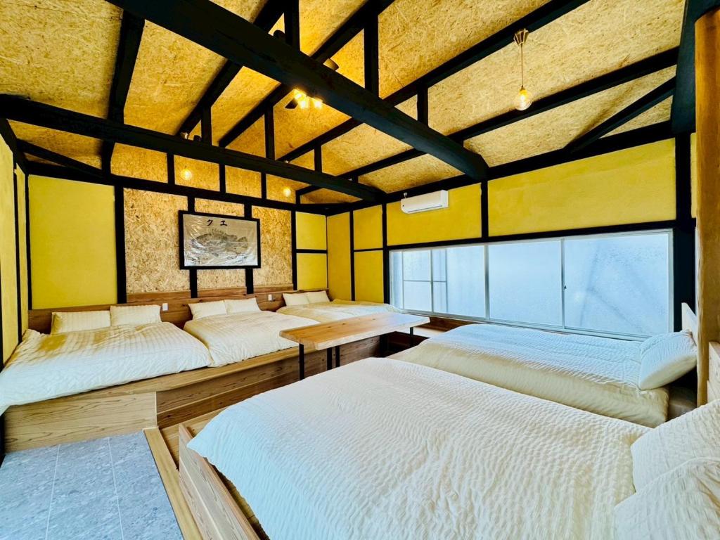 a room with four beds in it with yellow walls at 風乃釣り宿 in Shirahama